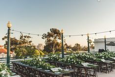 an outdoor dining area with tables and chairs covered in white flowers, surrounded by string lights