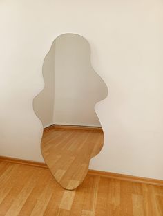 a mirror sitting on top of a hard wood floor next to a white wall in an empty room