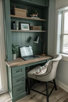 a laptop computer sitting on top of a wooden desk next to a chair in front of a window