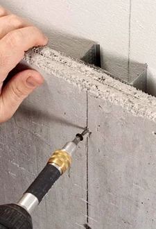 a person using a drill to fix a hole in a wall with cement and concrete mortar