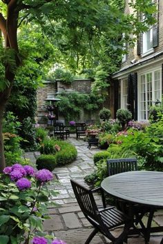 an outdoor patio with tables and chairs surrounded by greenery