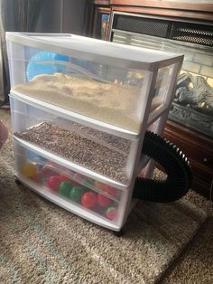 two plastic bins filled with sand and balls on the floor next to a fireplace