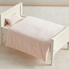 a small white bed with pink sheets and pillows