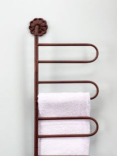 a towel rack with two white towels hanging from it's sides and a flower on the top