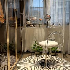 a white chair sitting on top of a rug in front of a glass cabinet and window