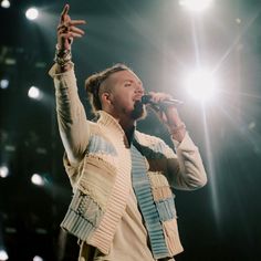 a man with dreadlocks on his head holding a microphone in front of him