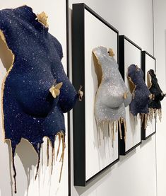 three paintings on the wall with gold and silver paint dripping from them, each one being a woman's breast