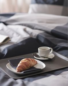 a tray with a croissant and coffee on it