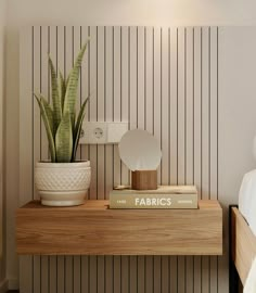 a bed room with a neatly made bed and a potted plant on the nightstand