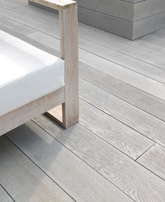 a white bed sitting on top of a wooden floor next to two cement planters