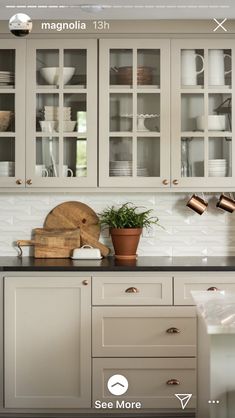 a kitchen with white cabinets, black counter tops and wooden utensils on the counters