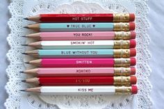 six colored pencils with writing on them sitting on a doily next to each other