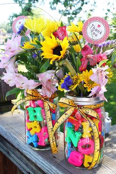 two mason jars filled with colorful flowers sitting on top of a wooden table next to each other