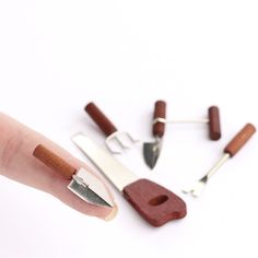 a hand with some scissors and other tools on it's finger, next to them