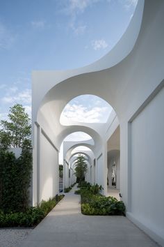 an archway between two buildings with trees and bushes on either side, leading into the distance