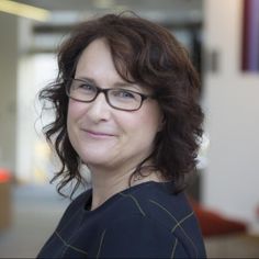 a woman with glasses smiling at the camera