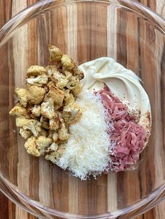 a glass bowl filled with food on top of a wooden table