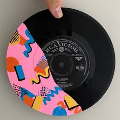 a hand is pointing at a record on the wall with colorful patterns and shapes painted on it