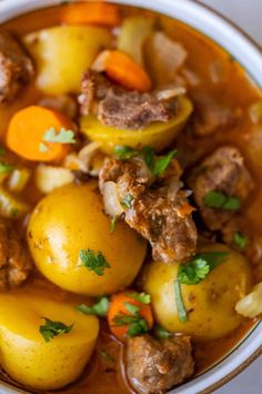 a white bowl filled with stew and potatoes