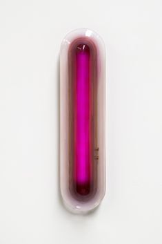 a pink object on a white surface in the shape of a tube