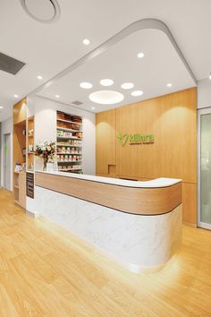 the front desk of a pharmacy with wooden floors and white counter top, along with shelves filled with medical supplies