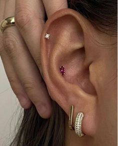 a woman is wearing two different ear piercings