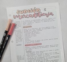 two pens sitting on top of a piece of paper with spanish writing in front of it