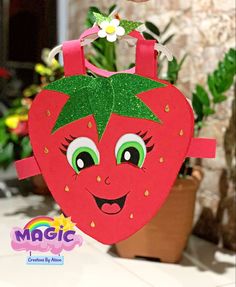 a paper bag with a strawberry on it is hanging from a hook in front of a potted plant