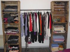 an open closet with clothes hanging on wooden shelves