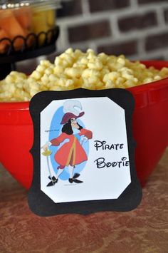 a red bowl filled with yellow popcorn next to a sign that says pirate beret