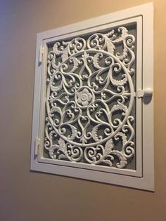 an intricately designed window on the side of a wall in a room with beige walls