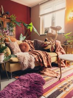 a living room filled with lots of furniture and plants on top of a colorful rug