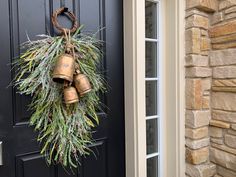 a wreath with bells hanging from it's side on the front door, next to a black door