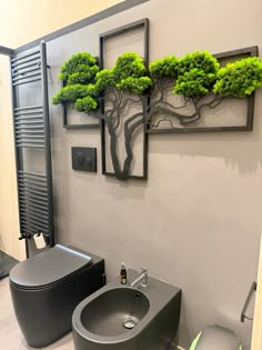 a bathroom with a toilet, sink and green trees on the wall above it's tank