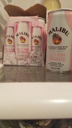 three cans of pink drink sitting on top of a refrigerator