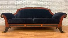 a black couch sitting on top of a hard wood floor next to a brick wall