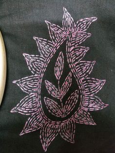 a black shirt with pink and white designs on the front is next to a banana