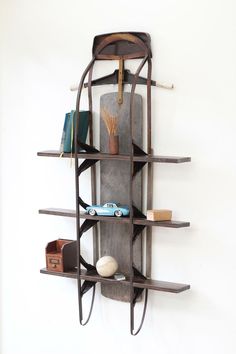 a wall mounted shelf with books and other items on it's sides, against a white wall