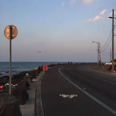 an empty street next to the ocean at sunset