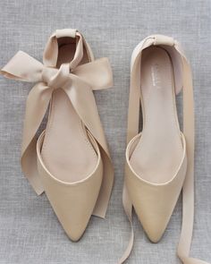 a pair of nude colored shoes with a bow on the toe and heels that are tied together