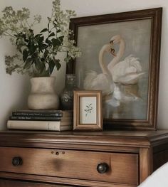 there is a painting and flowers on the dresser