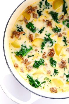 a casserole dish with meat, cheese and spinach in it on a white surface