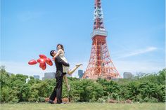 a man and woman are holding red balloons in front of the eiffel tower