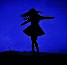 a woman standing in the dark with her arms spread out and hair blowing in the wind