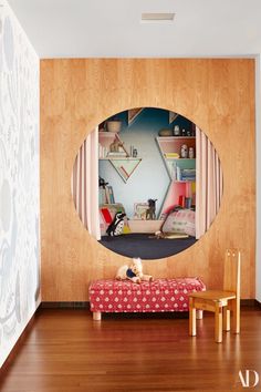 a dog is sitting on a bench in front of a mirror that shows a bedroom