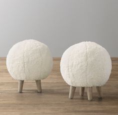 two white sheep stools sitting on top of a wooden floor next to each other