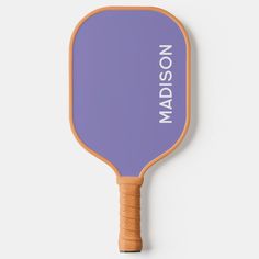 a purple wooden paddle with the name madison on it and an orange rubber handle is shown against a white background