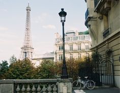 a bicycle parked next to a lamp post in front of the eiffel tower