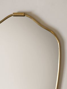 a mirror that is on the wall with a gold frame and metal bar around it