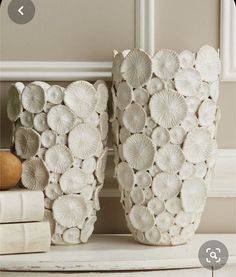 two white vases sitting on top of a table next to books and an apple